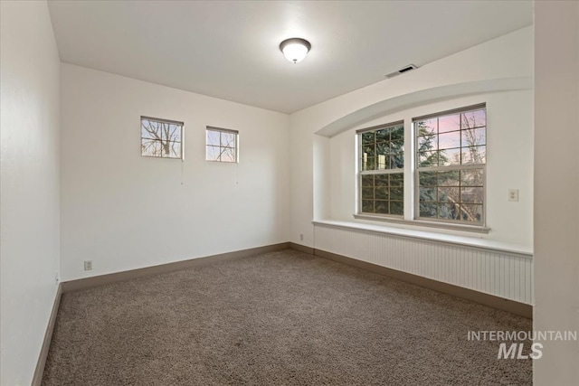 carpeted empty room featuring baseboards and visible vents