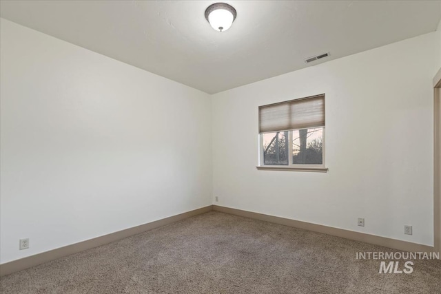 carpeted spare room featuring visible vents and baseboards