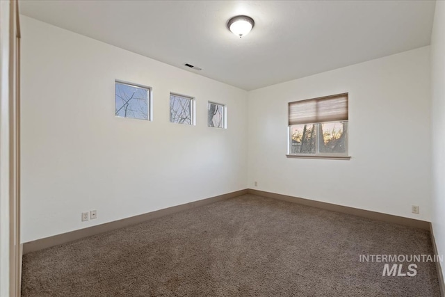 empty room featuring carpet, visible vents, and baseboards