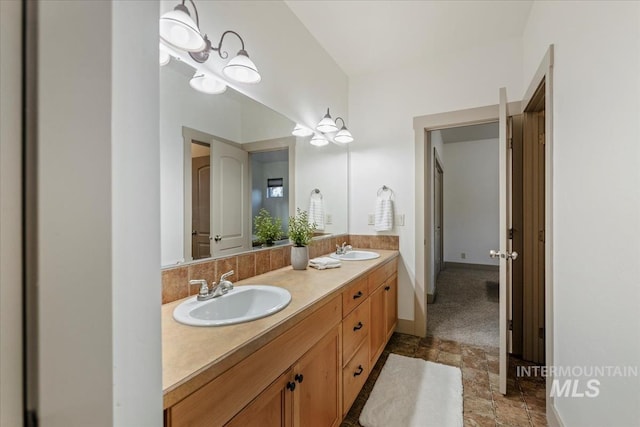 full bathroom featuring double vanity, stone finish floor, baseboards, and a sink