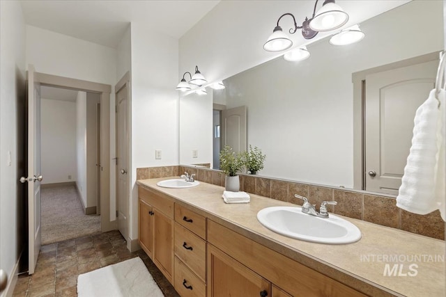 full bath featuring double vanity, baseboards, and a sink