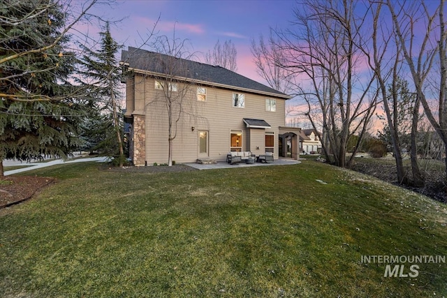 back of property at dusk with a yard, a patio, and outdoor lounge area