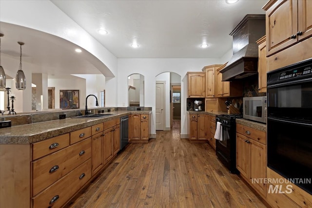 kitchen with dark wood-style flooring, a sink, black appliances, custom range hood, and pendant lighting