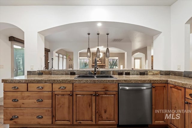 kitchen with visible vents, brown cabinets, a sink, stainless steel dishwasher, and tile countertops