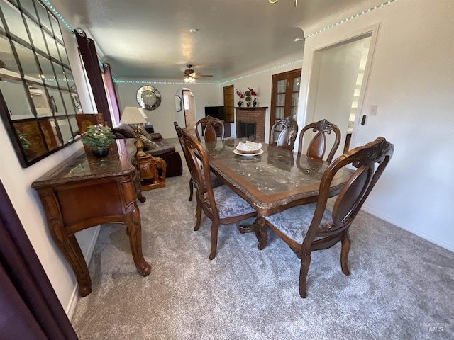 dining room with crown molding, a fireplace, carpet, and ceiling fan