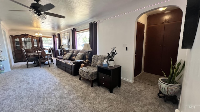 carpeted living room with a textured ceiling and ceiling fan with notable chandelier