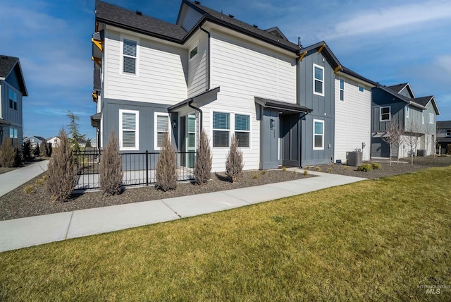 traditional-style house with a front lawn, central AC unit, board and batten siding, and a residential view