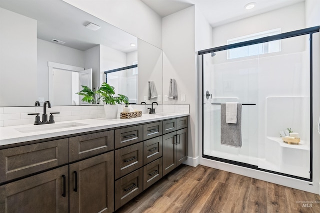 bathroom featuring tasteful backsplash, wood finished floors, a stall shower, and a sink