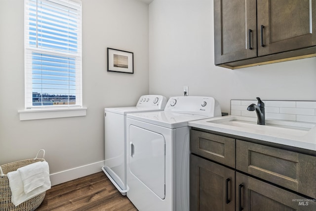 washroom with baseboards, washer and clothes dryer, dark wood-style floors, cabinet space, and a sink