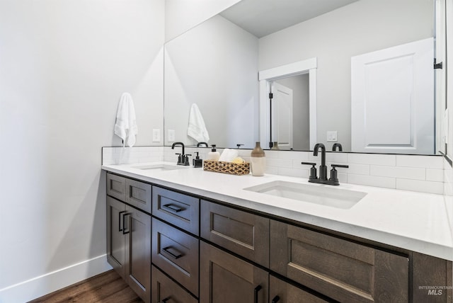 full bath with wood finished floors, baseboards, backsplash, and a sink