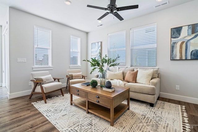 living room featuring visible vents, baseboards, and wood finished floors