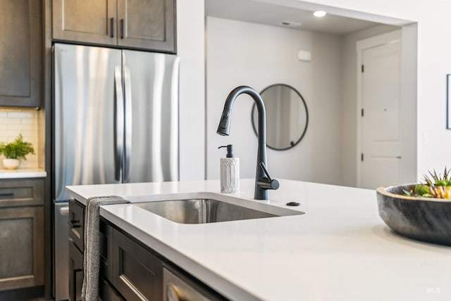 kitchen featuring recessed lighting, freestanding refrigerator, a sink, light countertops, and backsplash