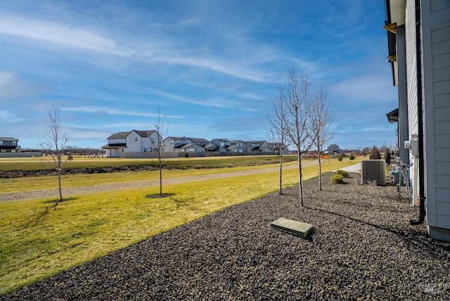 view of yard featuring a residential view and central AC unit