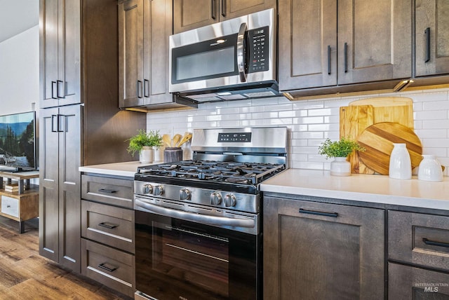 kitchen featuring dark brown cabinets, backsplash, dark wood-type flooring, light countertops, and appliances with stainless steel finishes