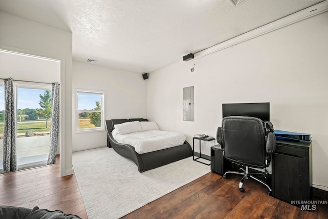 bedroom featuring access to exterior, electric panel, dark hardwood / wood-style flooring, and a textured ceiling