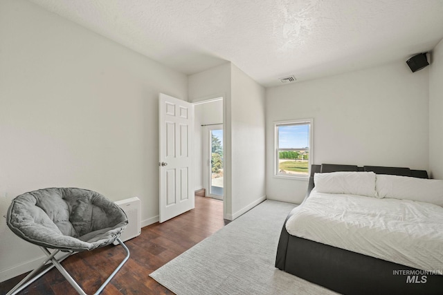 bedroom featuring a textured ceiling and dark hardwood / wood-style flooring