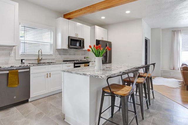 312 4th Ave, Lewiston, ID 83501 - kitchen featuring stainless steel appliances, a sink, healthy amount of natural light, a kitchen breakfast bar, and beamed ceiling