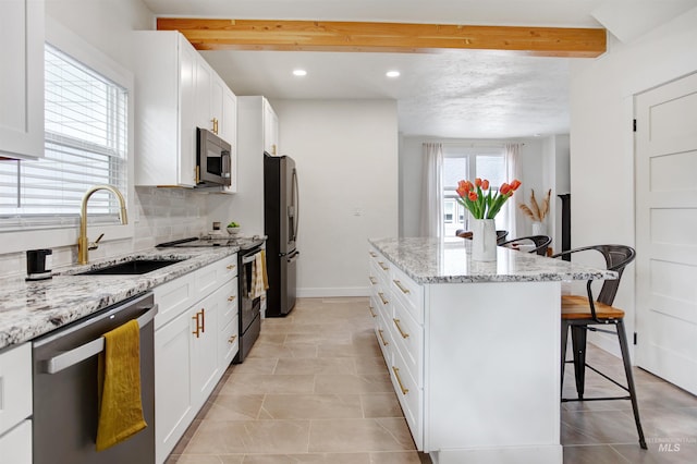 312 4th Ave, Lewiston, ID 83501 - kitchen featuring appliances with stainless steel finishes, a sink, a kitchen bar, a kitchen island, and white cabinetry