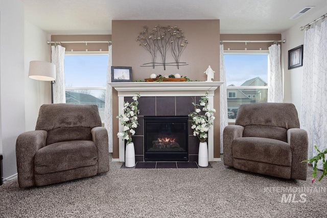 sitting room featuring carpet, plenty of natural light, and a tiled fireplace