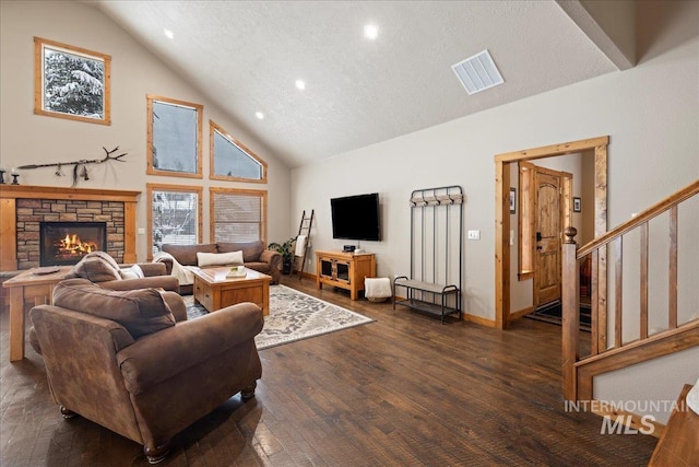 living room featuring dark hardwood / wood-style flooring, a textured ceiling, high vaulted ceiling, and a stone fireplace