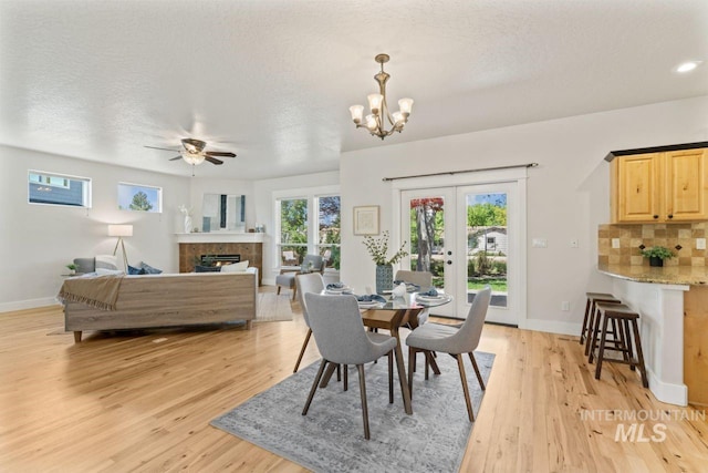 dining area with french doors, light wood-type flooring, a ceiling fan, and baseboards