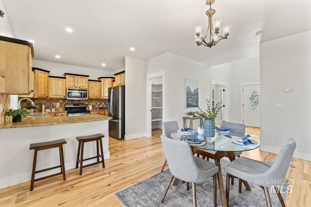 dining area with a chandelier, light wood-style floors, baseboards, and recessed lighting