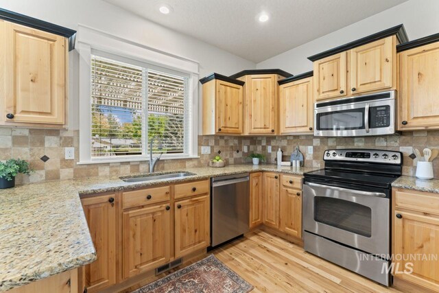 kitchen with stainless steel appliances, a sink, light brown cabinets, light wood-style flooring, and recessed lighting