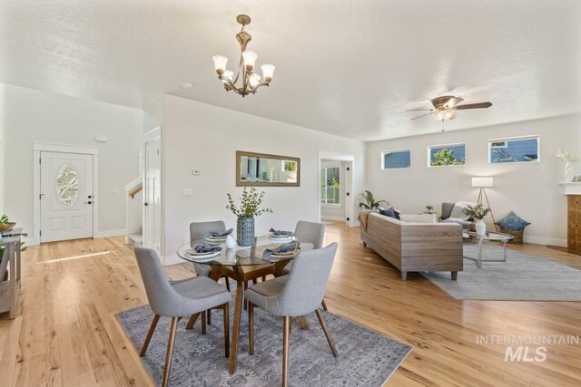 dining room with light wood finished floors, a chandelier, ceiling fan, and baseboards