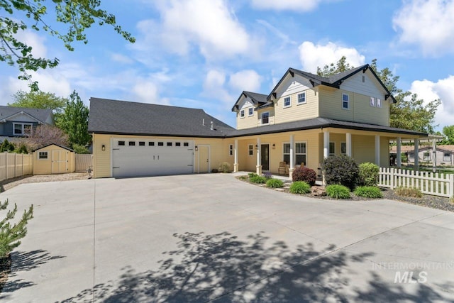 view of front of home with concrete driveway, covered porch, fence, an attached garage, and a shed