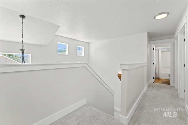 stairs with carpet floors, baseboards, plenty of natural light, and a textured ceiling