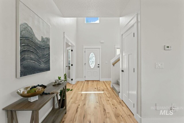foyer entrance with light wood finished floors, stairway, and baseboards