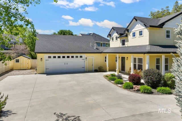 view of front of home with concrete driveway, an attached garage, fence, a porch, and a storage unit