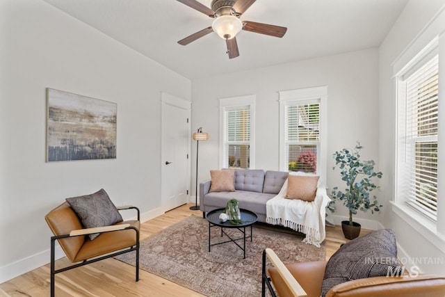 living area with light wood-style flooring, a ceiling fan, and baseboards