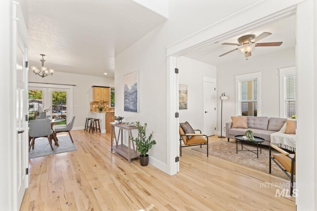 living room featuring light wood-type flooring, a chandelier, french doors, and ceiling fan