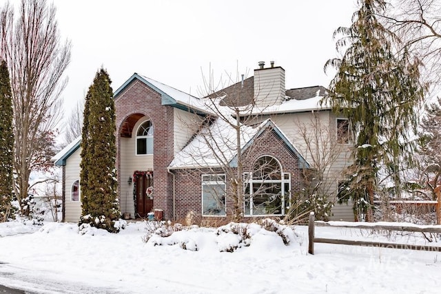 tudor home with brick siding and a chimney