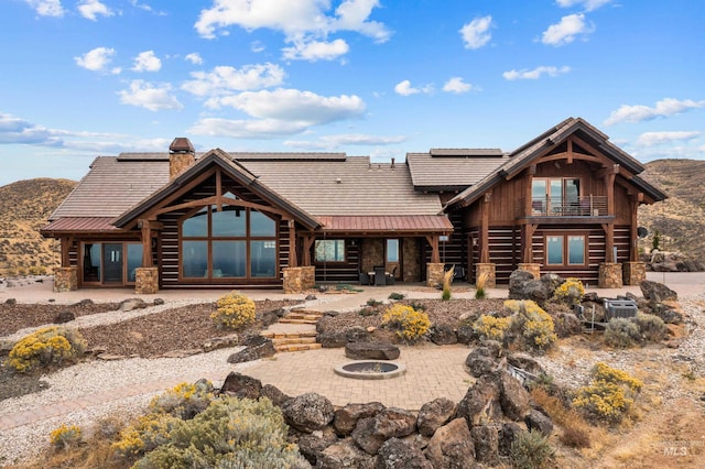 log cabin with a patio area, a mountain view, and an outdoor fire pit