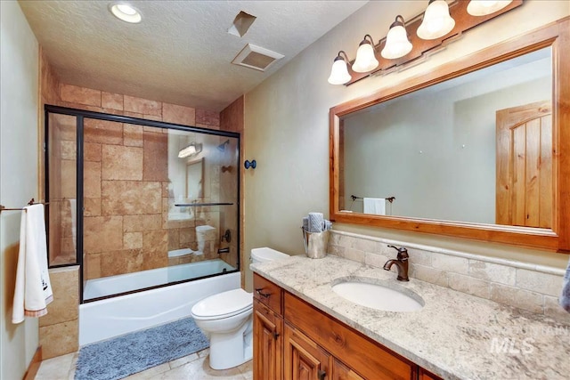 full bathroom with vanity, tile floors, a textured ceiling, toilet, and shower / bath combination with glass door