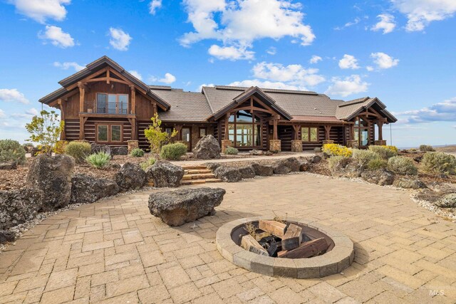 log home with an outdoor fire pit and a patio