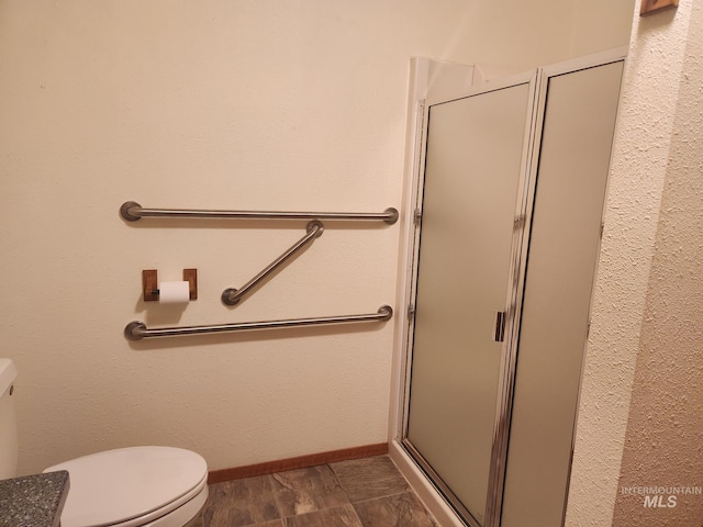 bathroom featuring hardwood / wood-style flooring, toilet, and a shower with door