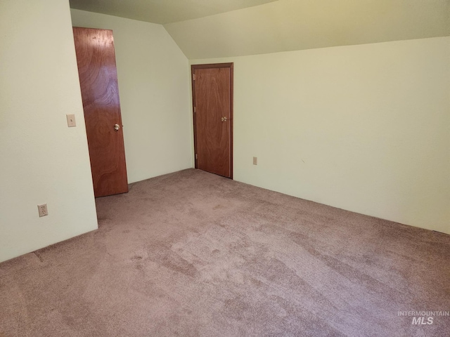 spare room with vaulted ceiling and light colored carpet