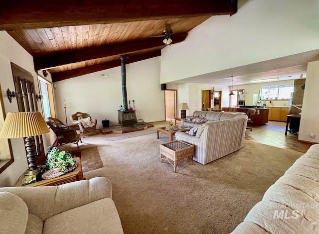 living area with a wood stove, wooden ceiling, carpet, and vaulted ceiling with beams