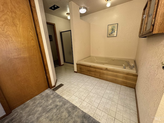 bathroom with visible vents, a textured wall, a shower stall, a textured ceiling, and a tub with jets