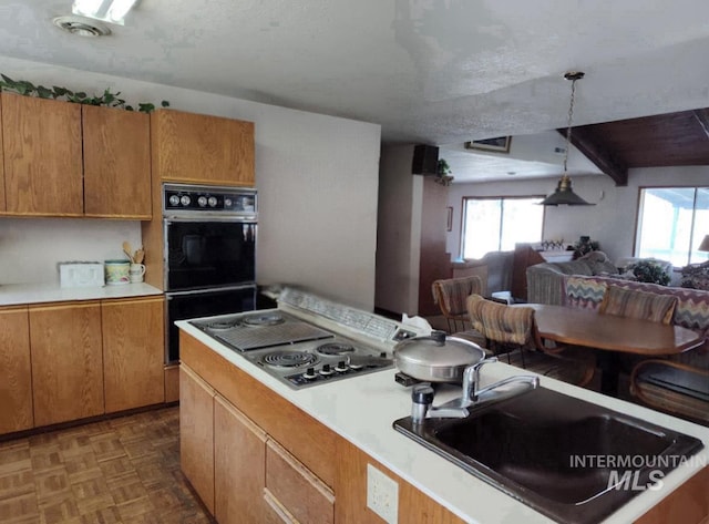 kitchen featuring light countertops, stovetop with downdraft, a sink, and dobule oven black