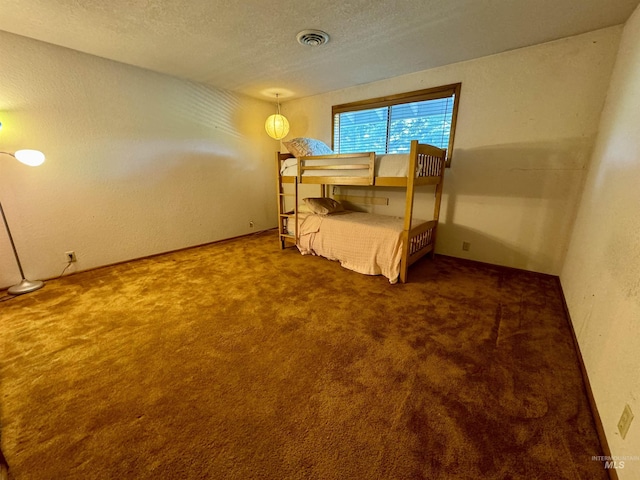 bedroom featuring visible vents, carpet flooring, a textured wall, and a textured ceiling