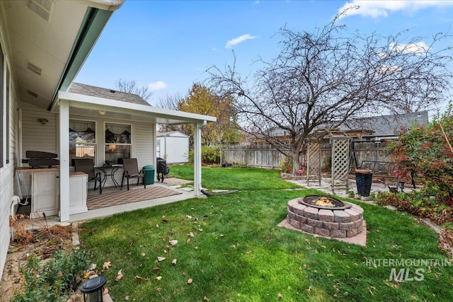 view of yard featuring a storage shed, a patio area, and an outdoor fire pit