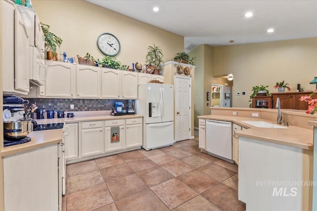 kitchen featuring backsplash, sink, white cabinets, and white appliances