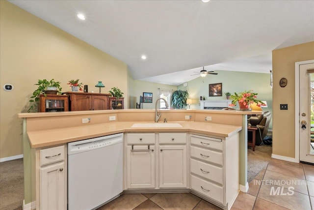 kitchen with dishwasher, sink, light tile patterned floors, vaulted ceiling, and white cabinets