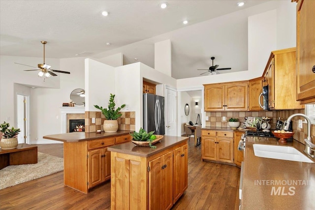 8613 W Thunder Mountain Dr, Boise, ID 83709 - kitchen featuring wood finished floors, decorative backsplash, appliances with stainless steel finishes, a kitchen island, and ceiling fan
