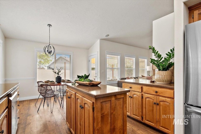8613 W Thunder Mountain Dr, Boise, ID 83709 - kitchen with lofted ceiling, hardwood / wood-style flooring, appliances with stainless steel finishes, a center island, and decorative light fixtures