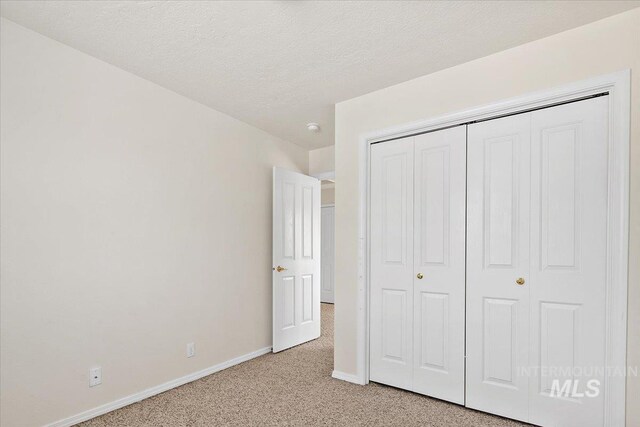 8613 W Thunder Mountain Dr, Boise, ID 83709 - unfurnished bedroom featuring a textured ceiling, a closet, baseboards, and light carpet